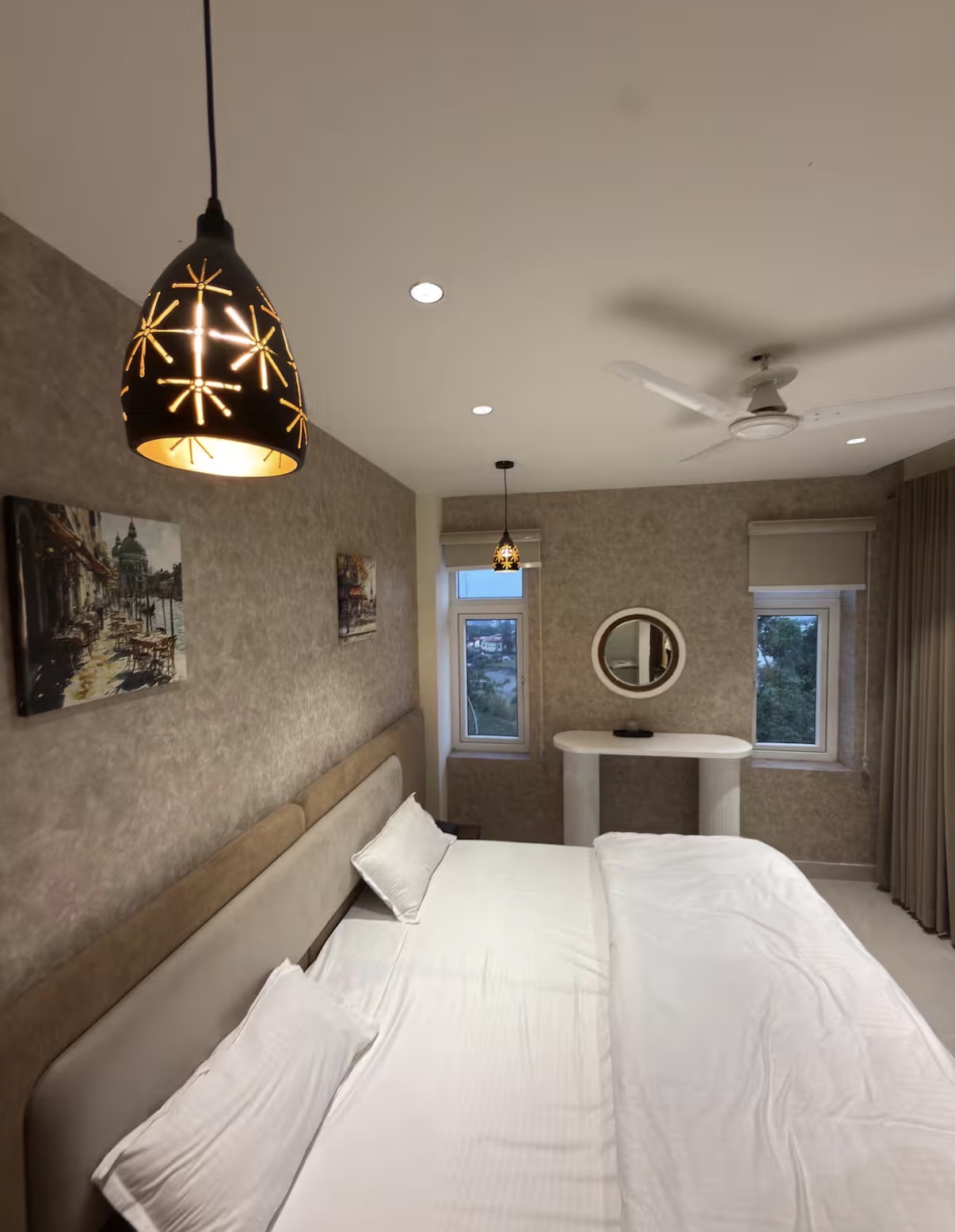 Bedroom with vanity and twin windows overlooking greenery