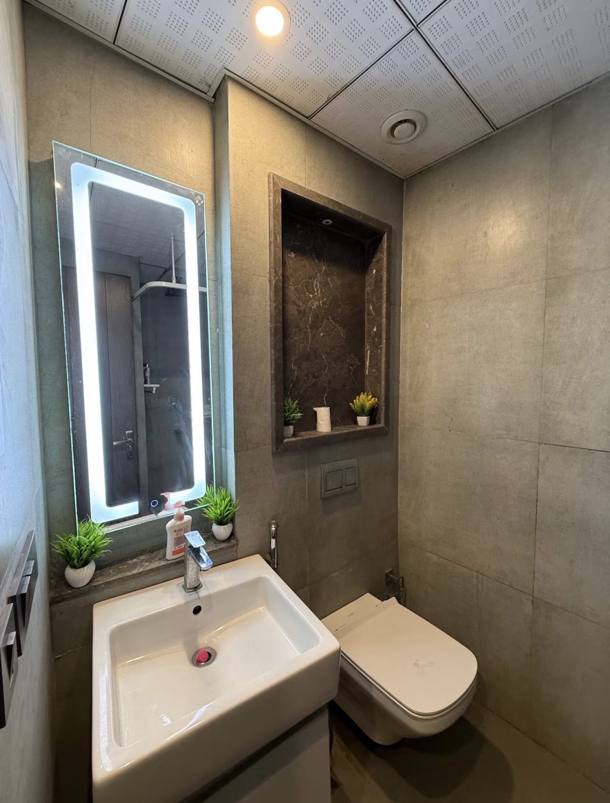 Modern powder room with backlit mirror and stone tiling