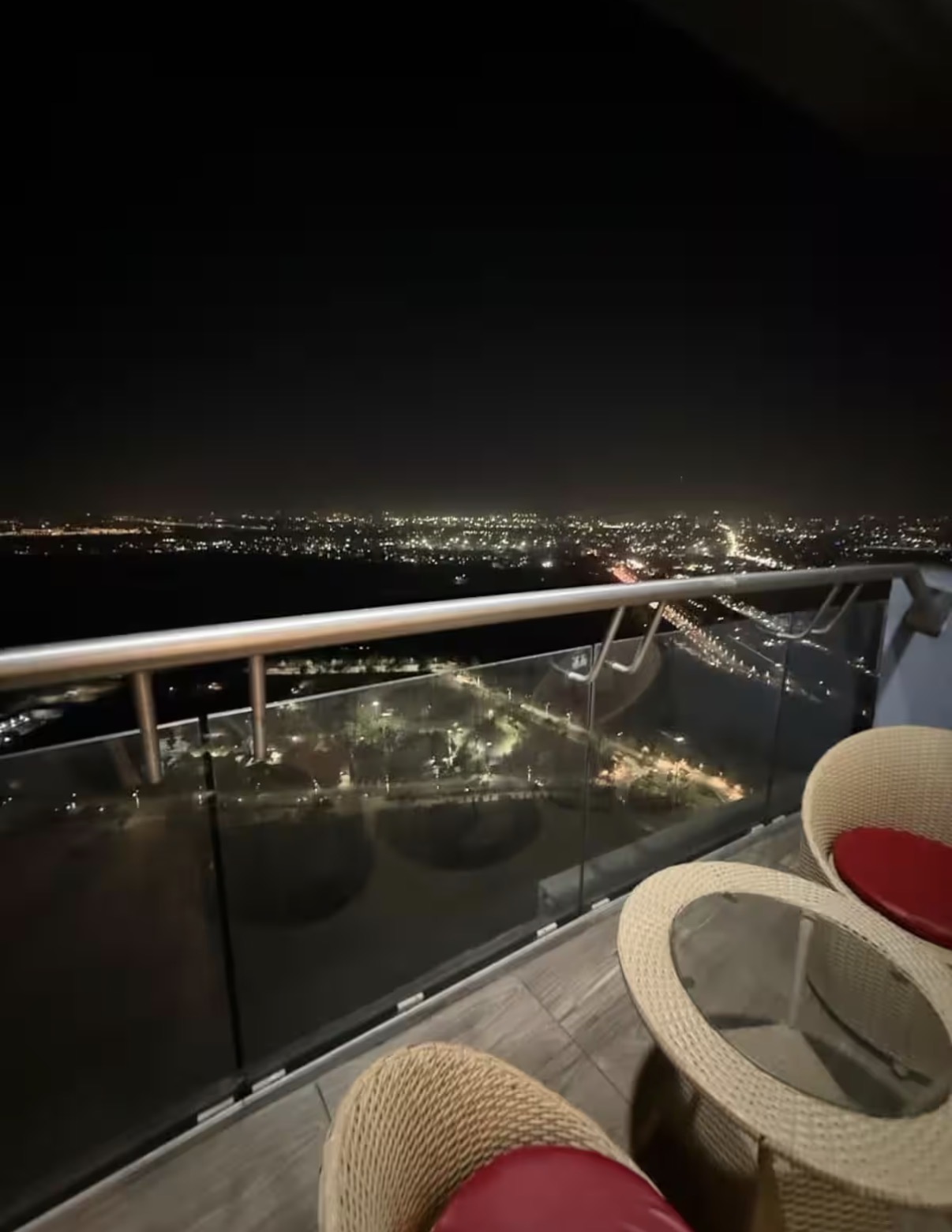Private balcony with cane seating and Noida city night lights